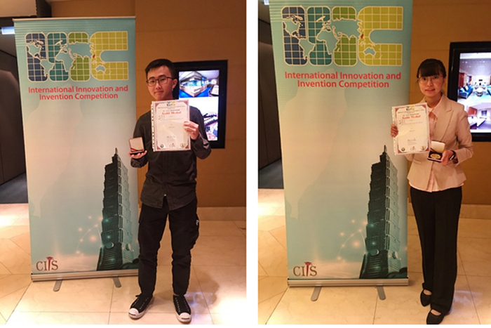 Two students proudly show their gold medal and certificate.