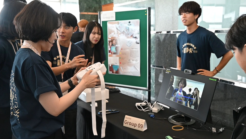 The second and third place winners of the 2025 ICDC secured the Excellence Prize, with their projects themed NEOFLIP 25 and Drawing Party, respectively. Pictured is Drawing Party, a game similar to "story relay" where participants draw in the air using a handheld device, with the images displayed on a screen. After the time limit, the participant must pass it to the next person to continue drawing, and the final artwork is then guessed by the players.